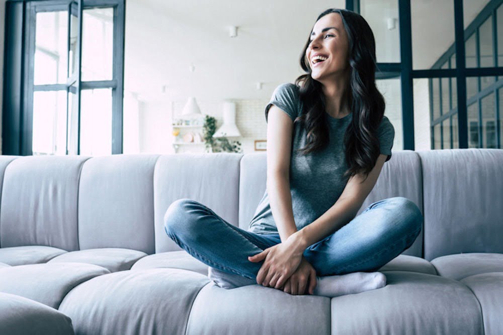 a woman laughing while sitting on a couch
