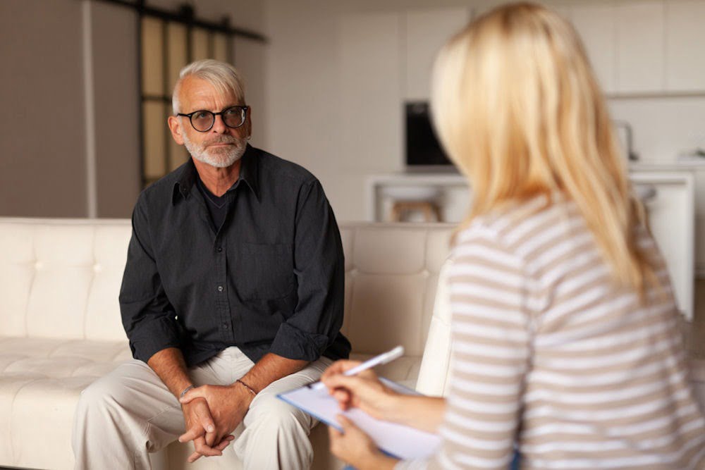 a man wearing glasses talking to therapist