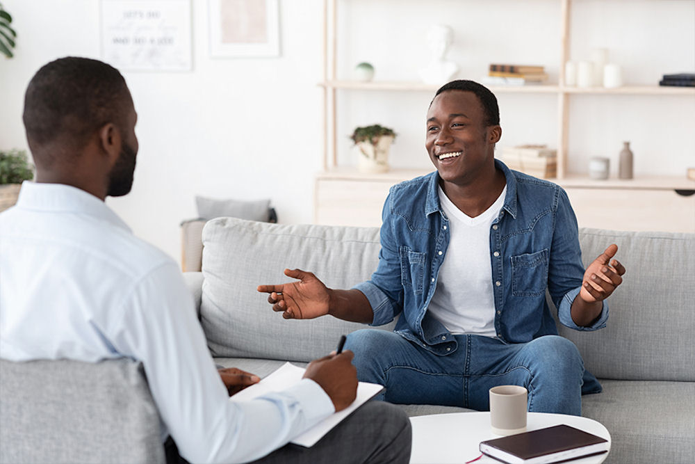 man in individual therapy, smiling while talking with his therapist