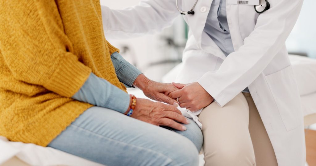 medical professional holding the hand of an elderly person