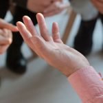 lose up of hands while a group of people sit in chairs and have a discussion