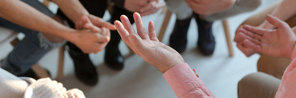 lose up of hands while a group of people sit in chairs and have a discussion