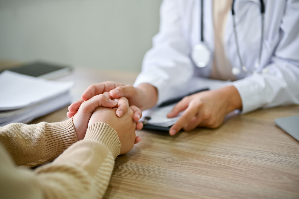 healthcare professional holding client's hand across table