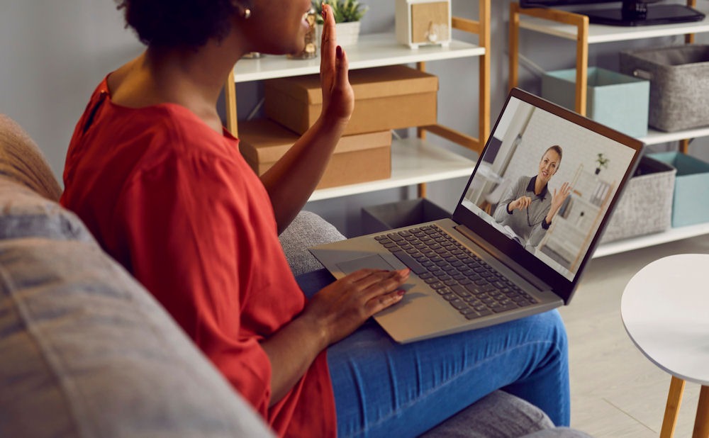 woman sitting on couch with laptop doing a telehealth therapy session