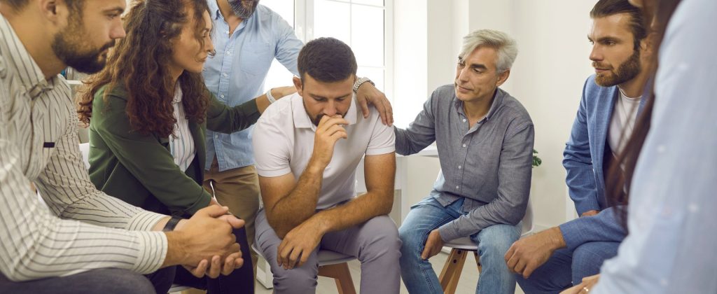 group of people surrounding a man and giving him support and comfort