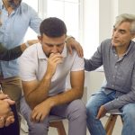 group of people surrounding a man and giving him support and comfort