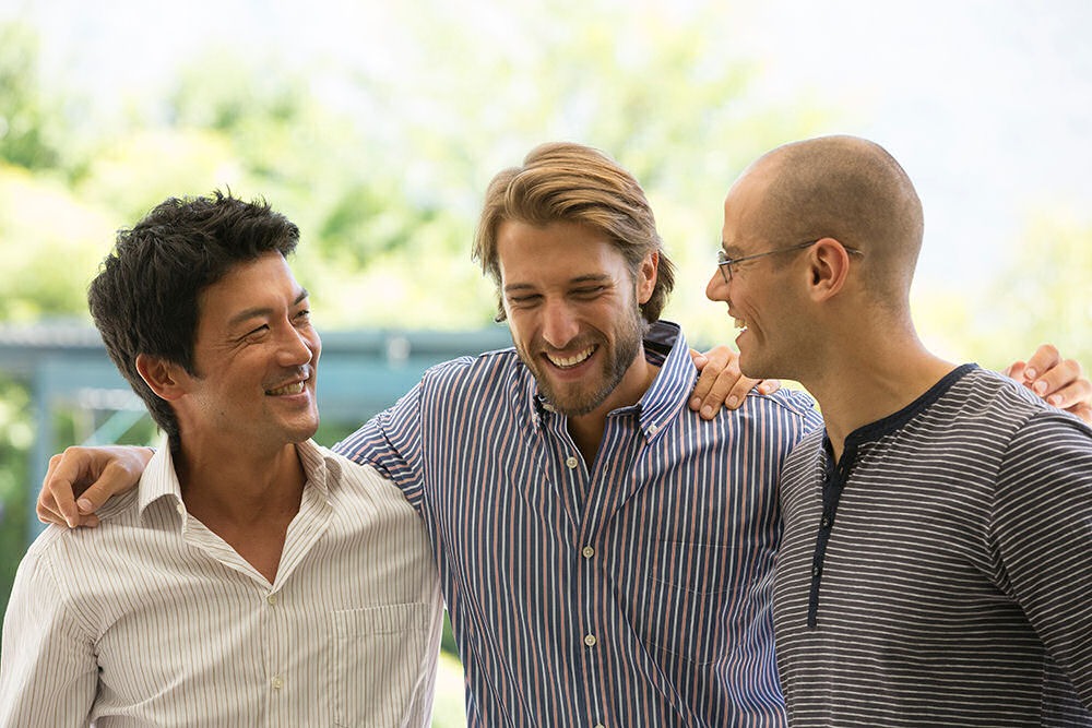 three men smiling with their arms around each other