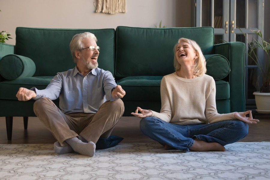 older couple sitting on the floor meditating and laughing