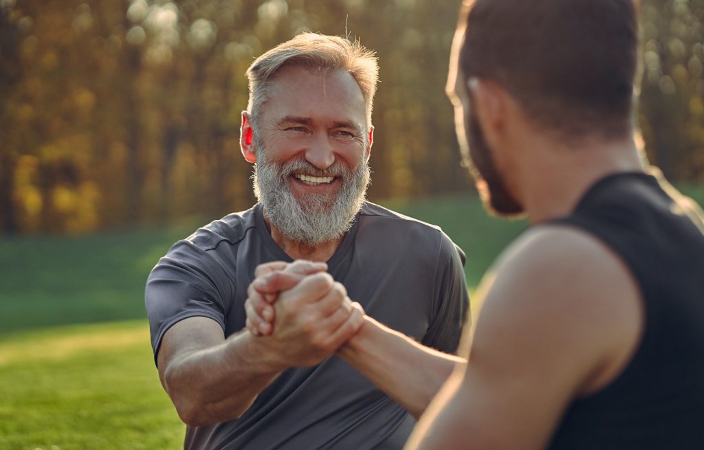 two men clasping hands and smiling