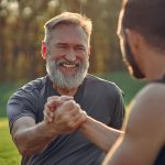 two men clasping hands and smiling