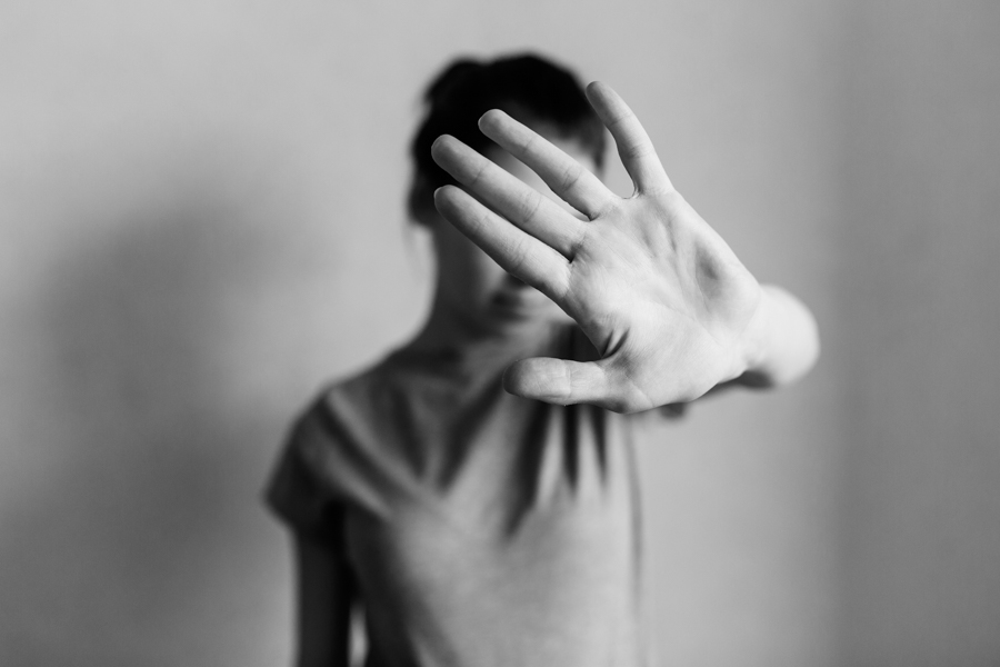 black and white photo of a woman putting hand up to camera to cover her face