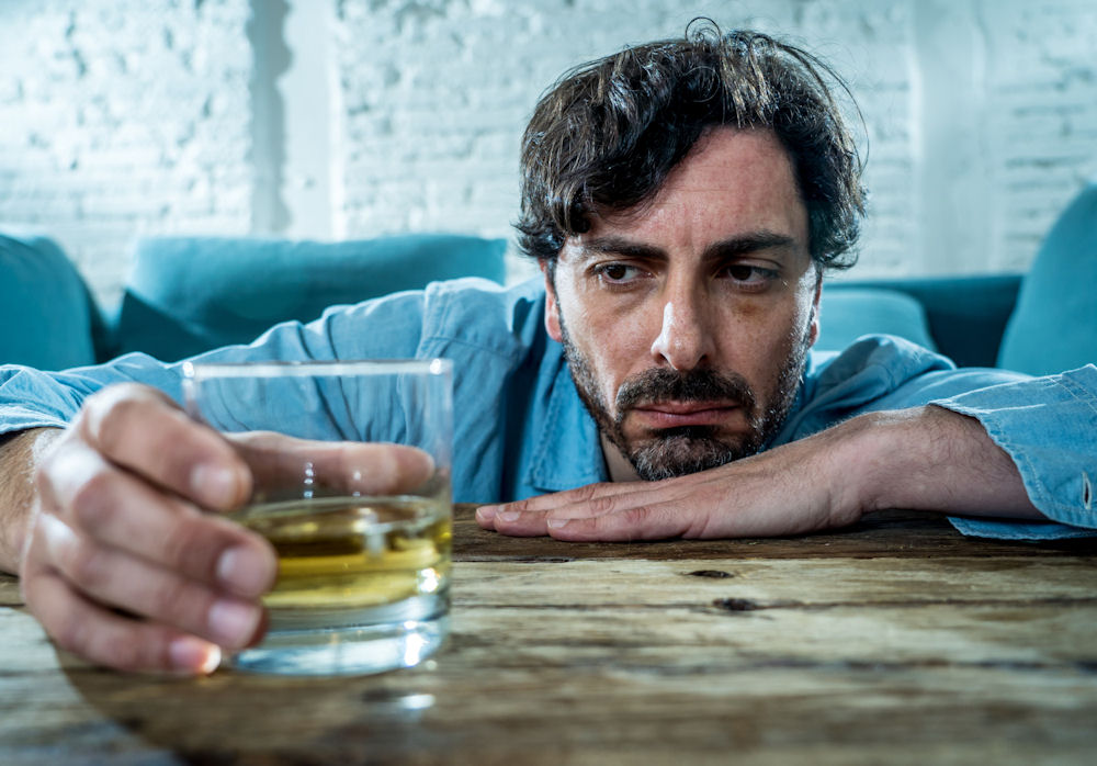 sad man looking at glass of alcohol