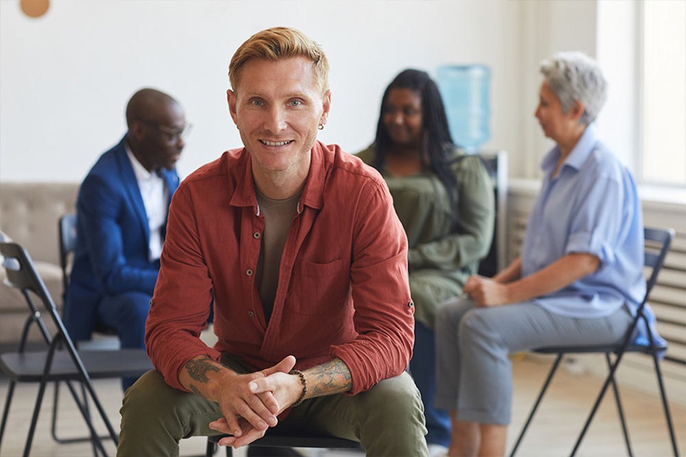 man smiling with addiction support group behind him