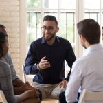 man in blue sweater addressing a small group in therapy