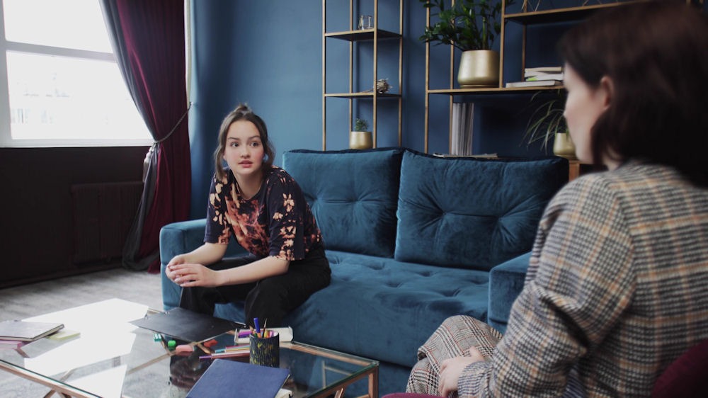 a teen sitting on couch while listening to her therapist