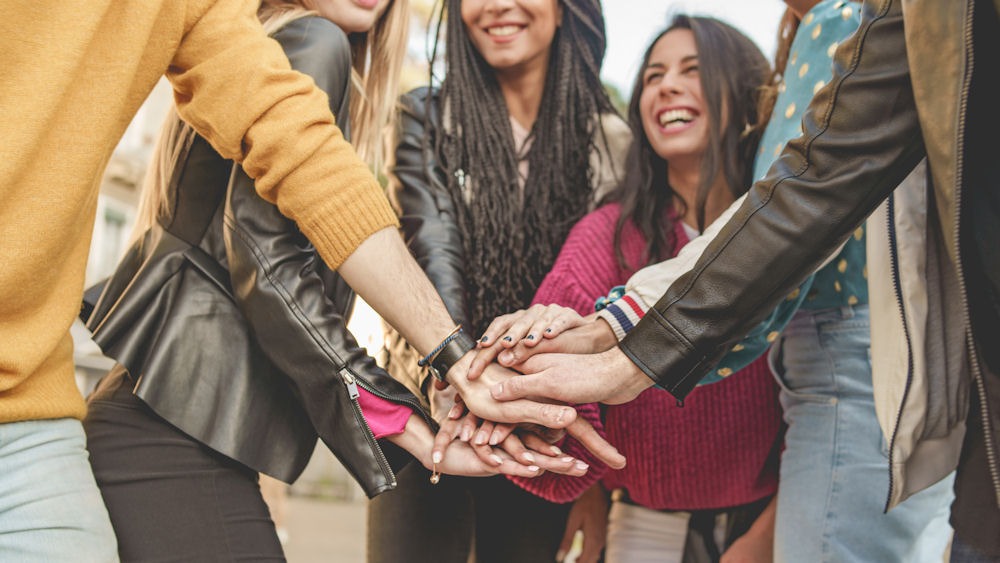 group of people putting their hands in a circle and smiling