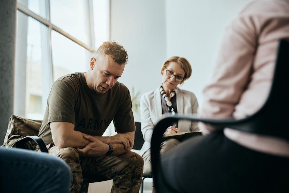 man with head down in group therapy