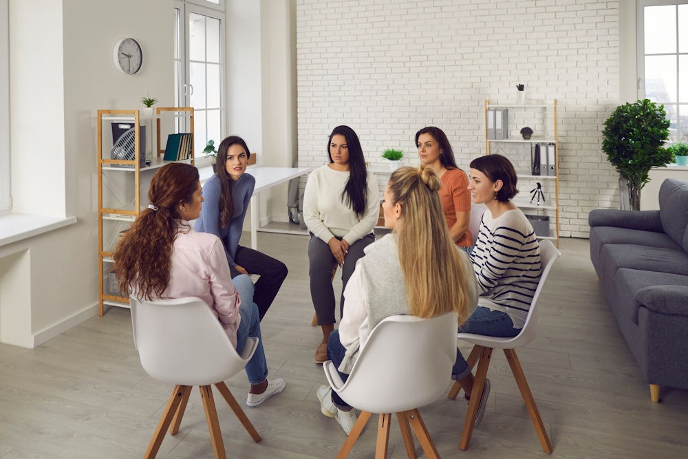 young adults sitting in circle of chairs