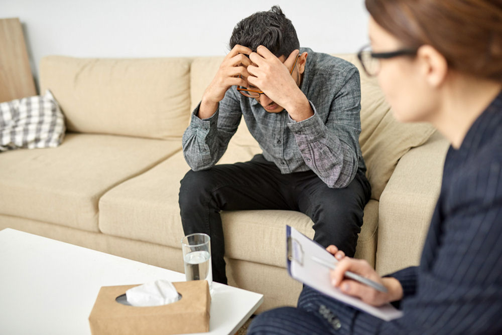 man in therapy holding his head