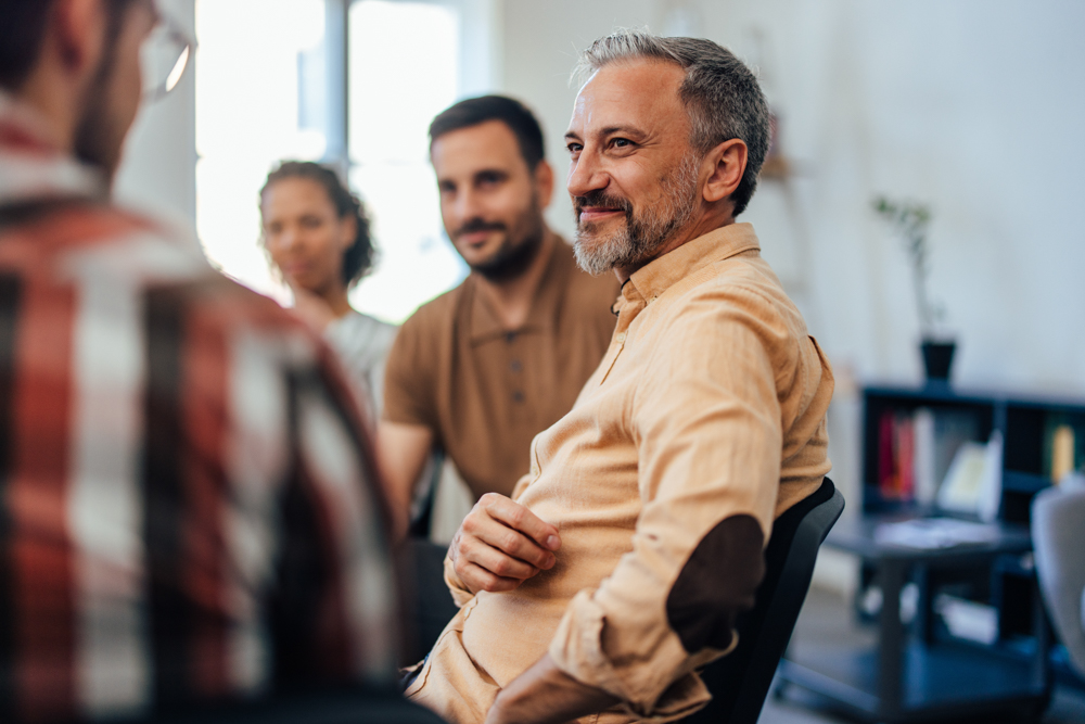 man smiling in group therapy for addiction