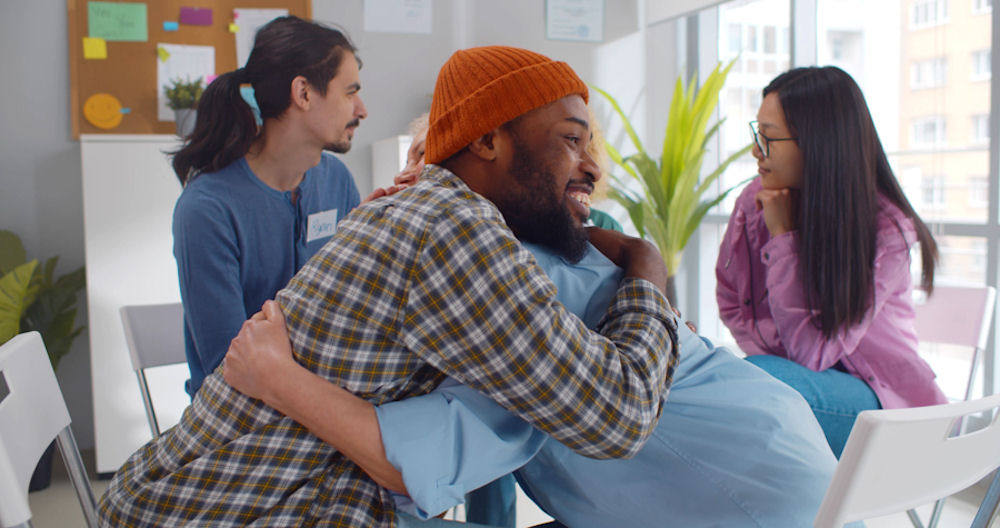 two men embracing in group therapy