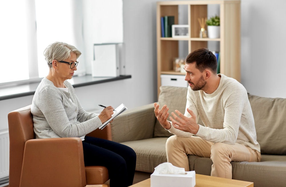 man in therapy, sitting on couch talking to therapist