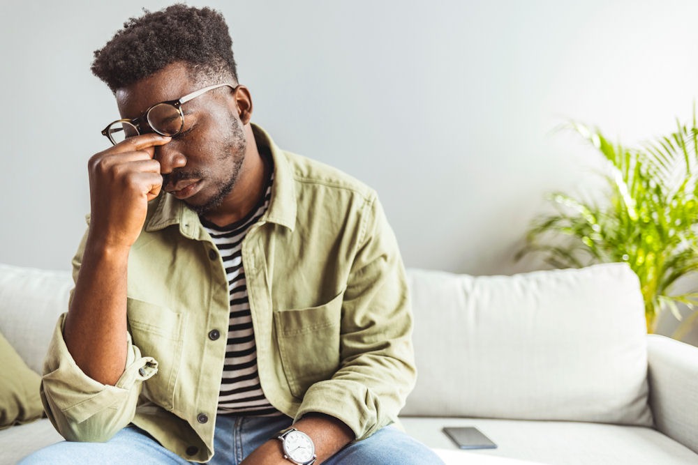 man pinching his nose looking upset