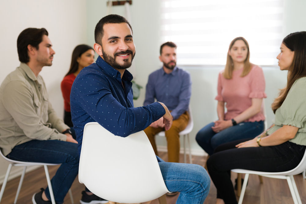 man turning back and smiling in group therapy