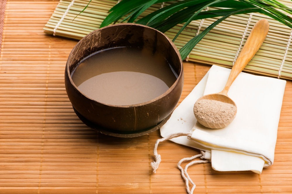 a bowl of liquid and a spoon of kava powder