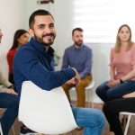 man turning back and smiling in group therapy