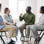 man in green shirt talking during group therapy